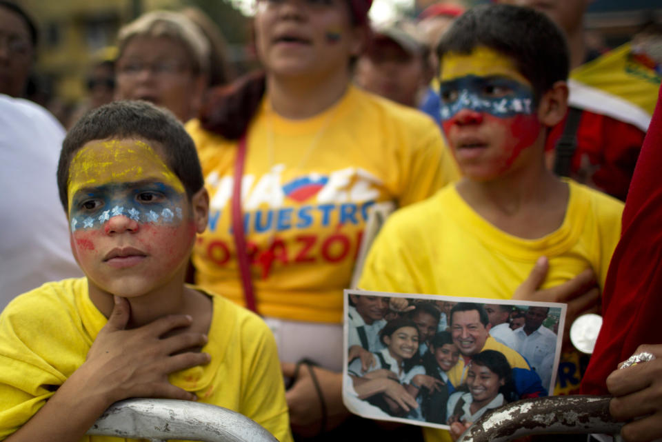 A boy sings Venezuela's national anthem outside the mausoleum of Venezuela's late President Hugo Chavez in Caracas, Venezuela, Wednesday, March 5, 2014. Venezuelans are commemorating the one year anniversary of Chavez's death. (AP Photo/Rodrigo Abd)