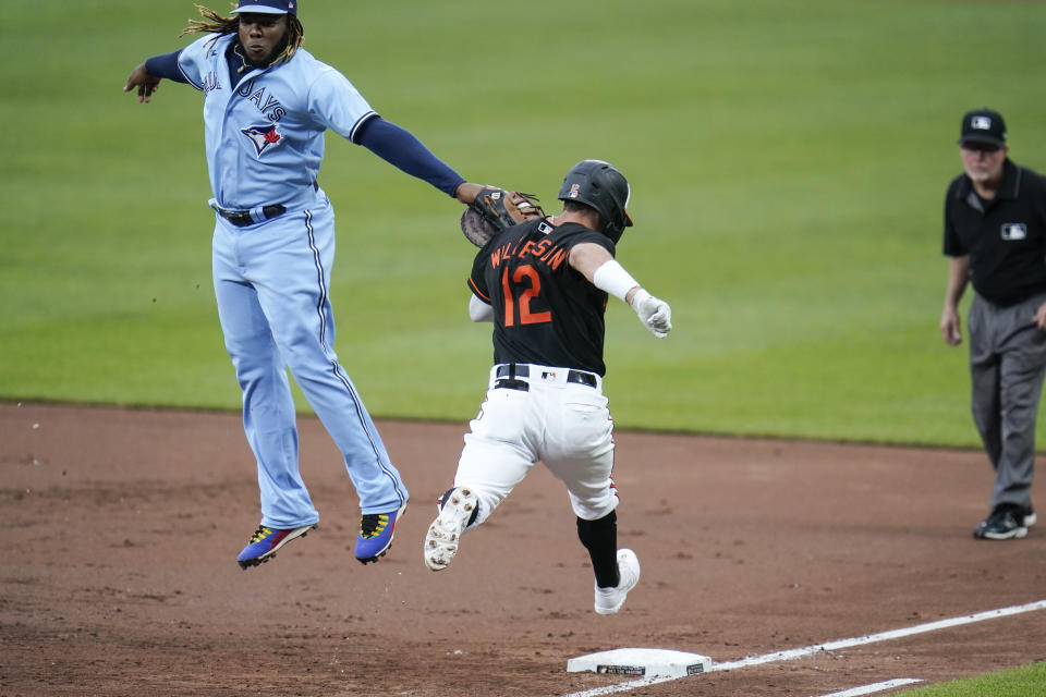 Toronto Blue Jays first base Vladimir Guerrero Jr., left, applies a tag on Baltimore Orioles' Stevie Wilkerson (12) for the out after going up to reach a throw from Blue Jays shortstop Marcus Semien during the third inning of a baseball game, Saturday, June 19, 2021, in Baltimore. (AP Photo/Julio Cortez)