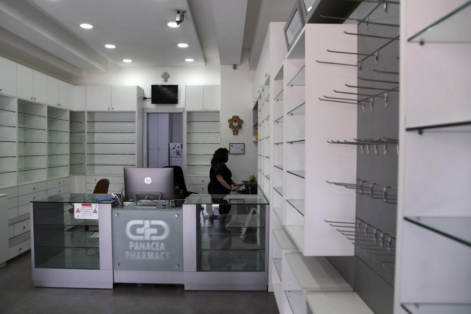 Pharmacist Rita El Khoury stands in the middle of her empty pharmacy after selling her stock in preparation for her move to France with her husband, in Ballouneh, north of Beirut, Lebanon, Wednesday, April 21, 2021. Driven by financial ruin, collapsing institutions, hyperinflation and rapidly rising poverty, the 35-year-old pharmacist is among thousands of young and middle-aged professionals who have left or are leaving the country in the latest wave of Lebanese immigration. (AP Photo/Bilal Hussein)