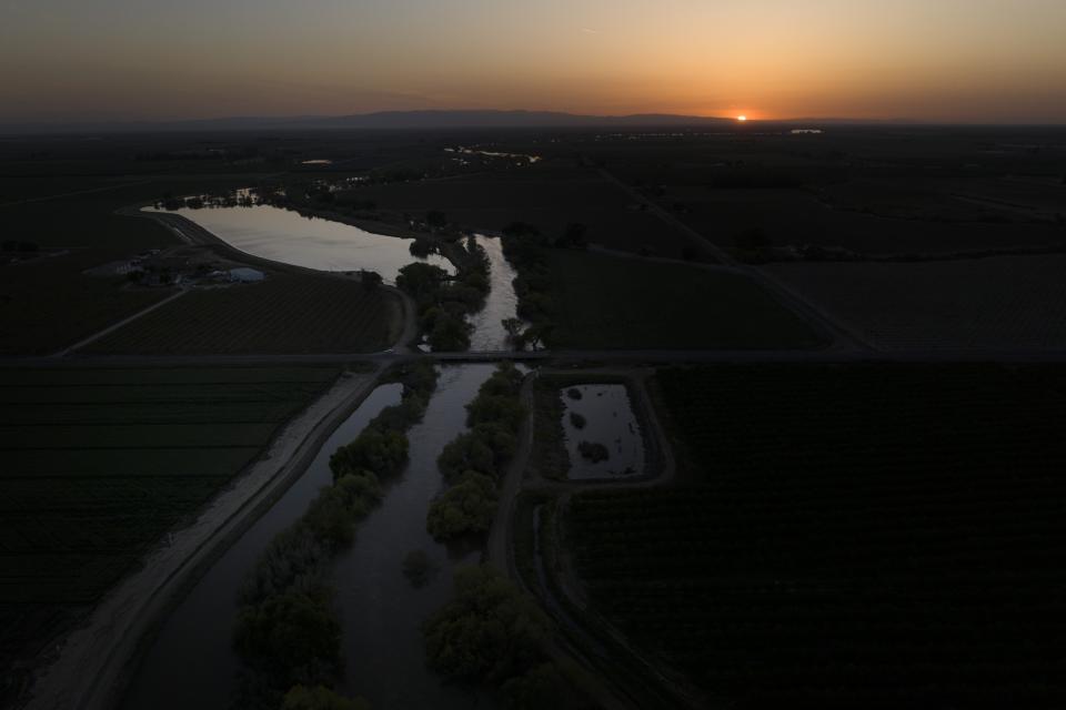 FILE - Twilight settles in over the North Fork Kings River in the Island District of Lemoore, Calif., as the sun sets over the horizon on April 19, 2023. California officials are considering whether to take over monitoring groundwater use in the fertile San Joaquin Valley under a landmark law aimed at protecting water flow to homes and farms. The Tuesday, April 16, 2024, hearing before the State Water Resources Control Board is the first of its kind since California passed a groundwater management law a decade ago. (AP Photo/Jae C. Hong, File)