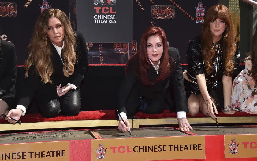 Lisa Marie Presley, left, Priscilla Presley and Riley Keough write their names in cement during a hand and footprint ceremony