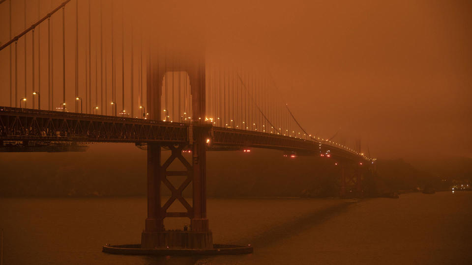 Cars drive along the Golden Gate Bridge under an orange smoke-filled sky at midday in San Francisco, September 9, 2020. There were 35 major wildfires burning in the state, with at least five towns 