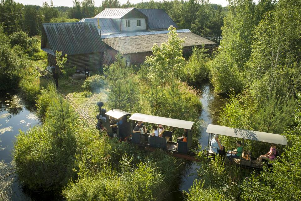 A miniature steam train runs across a bridge on Pavel Chilin's miniature personal narrow-gauge railway twisting through the grounds of his home in Ulyanovka village outside St. Petersburg, Russia Sunday, July 19, 2020. It took Chilin more than 10 years to build a 350-meter-long mini-railway twisting through the grounds of his cottage home about 50 kilometers (some 30 miles) outside St. Petersburg, complete with various branches, dead ends, circuit loops, and even three bridges.(AP Photo/Dmitri Lovetsky)