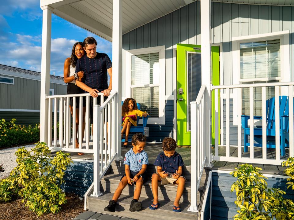 A family standing and sitting in front of a cabana cabin.