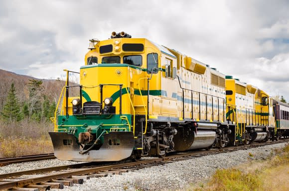 Yellow and green locomotive under a cloudy sky.