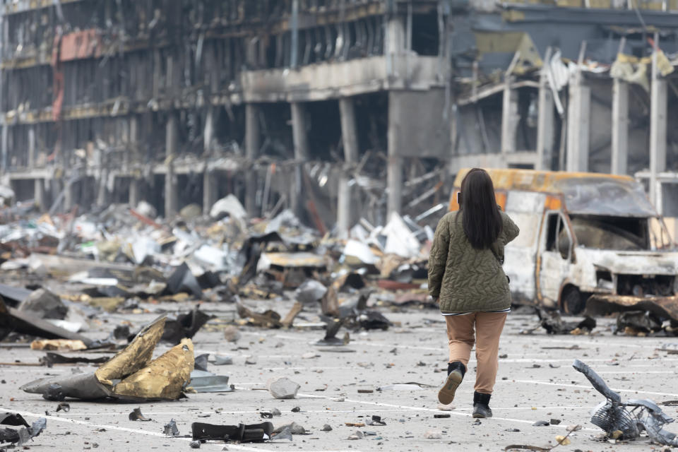 KYIV, UKRAINE - 2022/03/29: A young woman with a mobile phone takes pictures of a destroyed Retroville shopping center following a Russian shelling attack. Retroville shopping center including its surrounding areas in Kyiv are destroyed after the Russian shelling attack. According to the emergency service, at least six people died during the attack. Russia invaded Ukraine on 24 February 2022, triggering the largest military attack in Europe since World War II. (Photo by Mykhaylo Palinchak/SOPA Images/LightRocket via Getty Images)