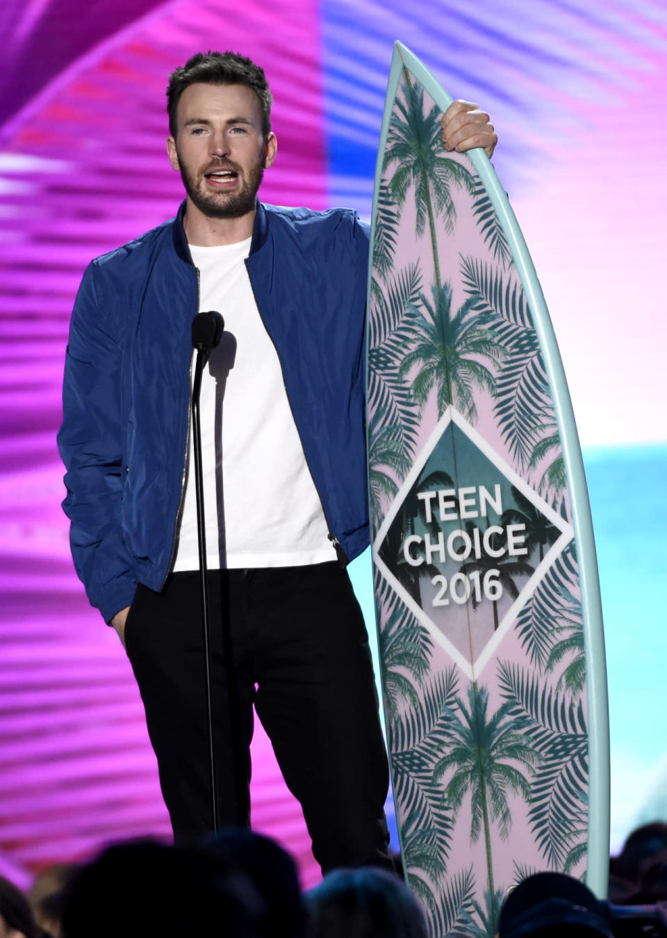 Chris Evans accepting his award in a royal-blue bomber jacket 