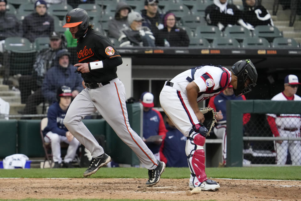 Baltimore Orioles' Adley Rutschman, left, scores on a one-run single by Anthony Santander as Chicago White Sox catcher Seby Zavala, right, looks down during the eighth inning of a baseball game in Chicago, Sunday, April 16, 2023. (AP Photo/Nam Y. Huh)