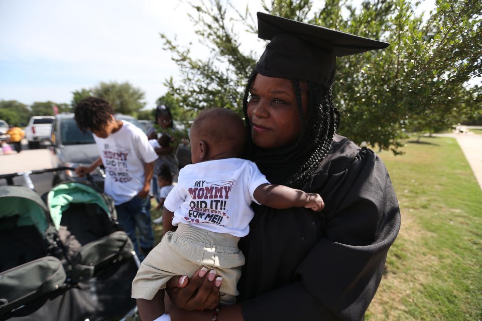 Before her graduation ceremony last week, Shilda Fresch holds a child she is in the process of adopting. The boy's shirt reads, "My Mommy Did It for Me."