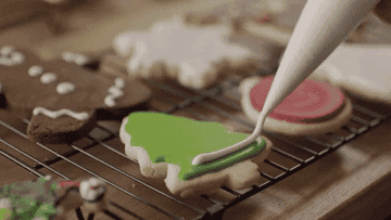 Someone decorating a Christmas cookie