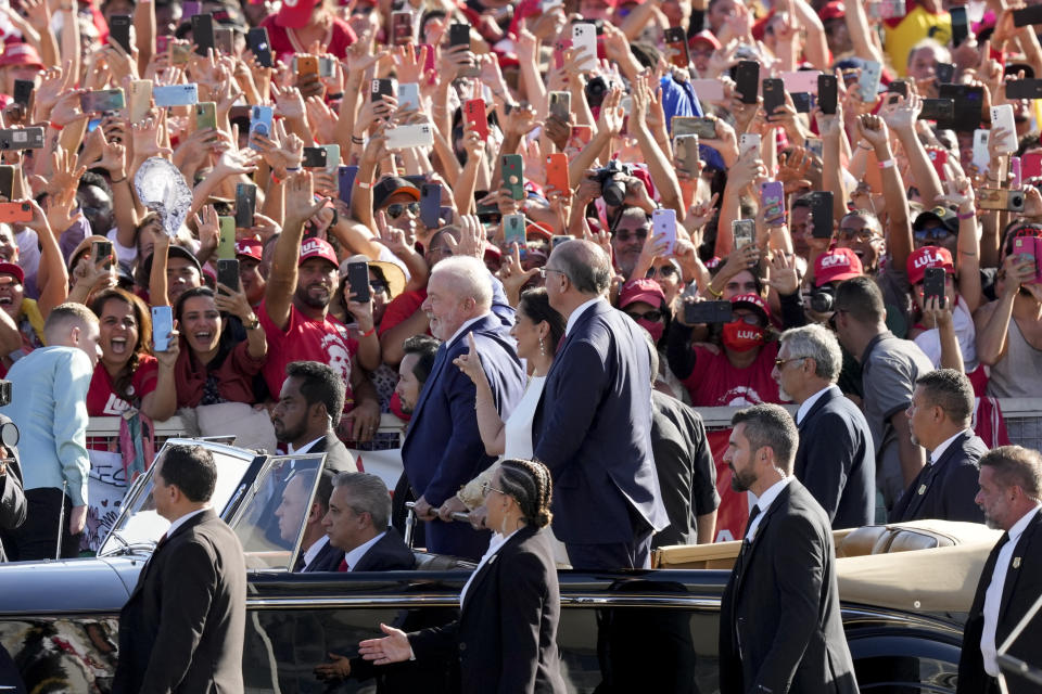 President Luiz Inacio Lula da Silva, right, Vice President Geraldo Alckmin, left, and his wife Maria Lucia Ribeiro, center, ride on an open car to the Planalto Palace in Brasilia, Brazil, Sunday, Jan. 1, 2023.(AP Photo/Eraldo Peres)