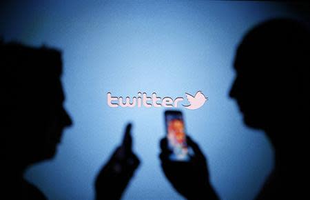 Men are silhouetted against a video screen with a Twitter logo as they pose with Samsung S3 and S4 smartphones in this photo illustration taken in the central Bosnian town of Zenica on August 14, 2013. REUTERS/Dado Ruvic/Files