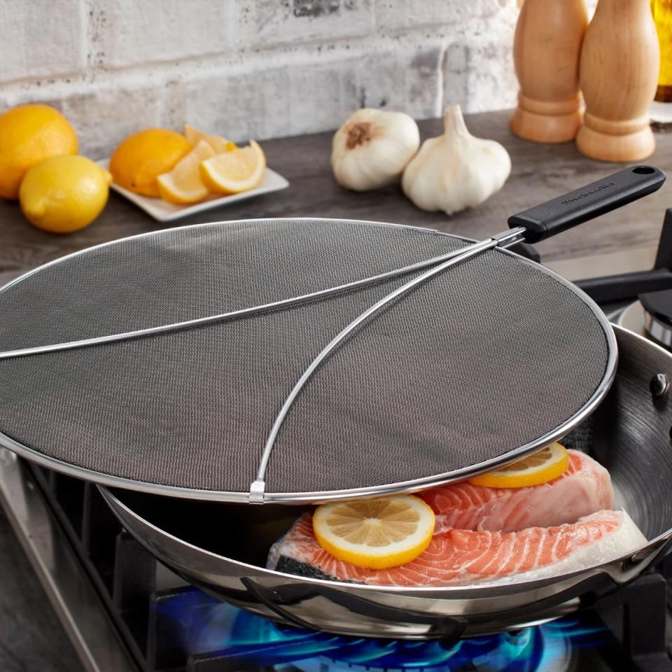 Splatter screen over a frying pan with fish and lemon slices inside