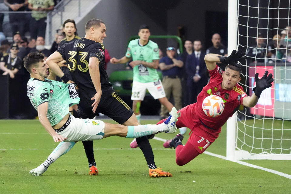 El portero del LAFC John McCarthy salta para intentar bloquear el disparo del mediocampista del León Lucas Di Yorio y el defensa del LAFC Aaron Long observa en el duelo de vuelta de la final de la Liga de Campeones CONCACAF el domingo 4 de junio del 2023. (AP Foto/Marcio Jose Sanchez)