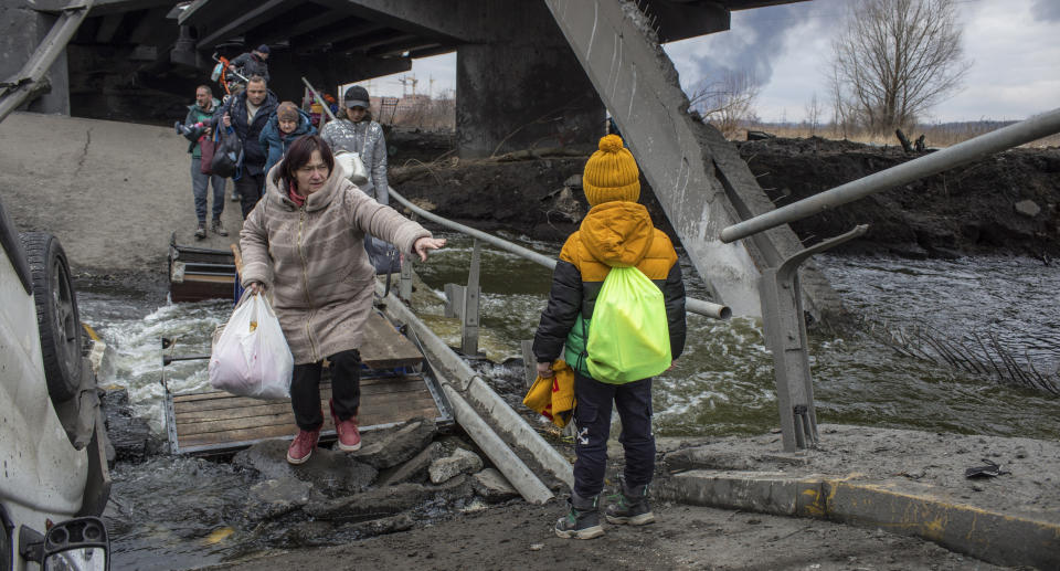 Civilians cross rubble at a damaged bridge in the Irpin city near from Kyiv (Kiev), Ukraine, on Sunday.