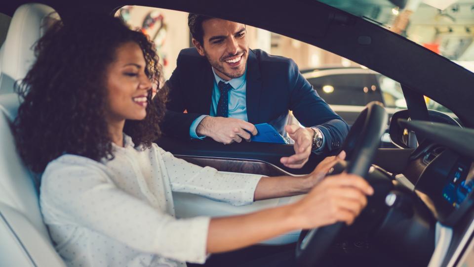 Smiling woman in the showroom enjoying luxury car.