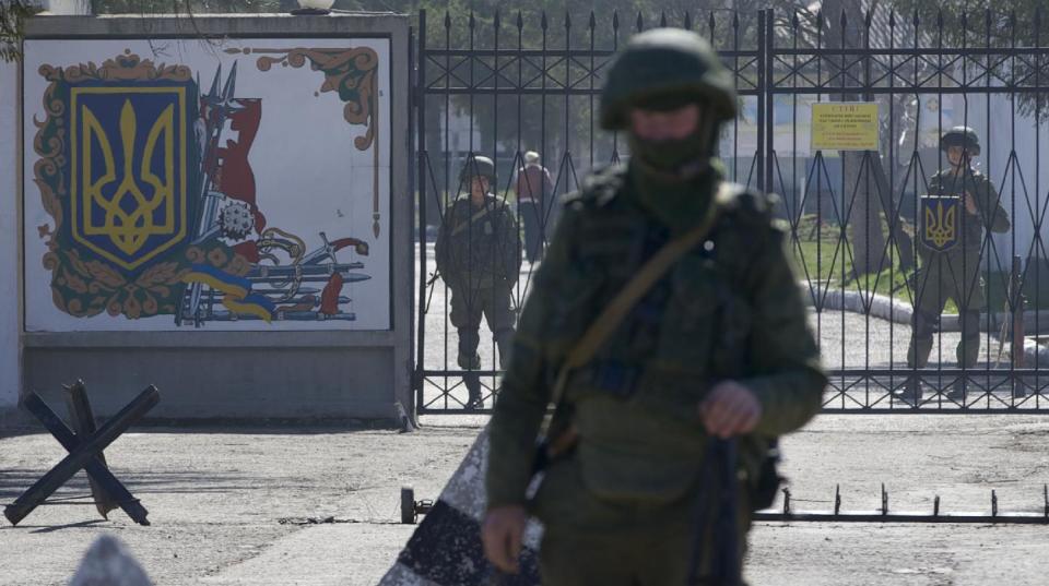 Russian soldiers guard the entrance to the Ukrainian military base in Perevalne, Crimea, on Friday, March 21, 2014. Russian President Vladimir Putin is expected today to sign the annexation of Ukraine’s Crimean Peninsula. The upper house of the Russian parliament approved the annexation earlier today. (AP Photo/Ivan Sekretarev)