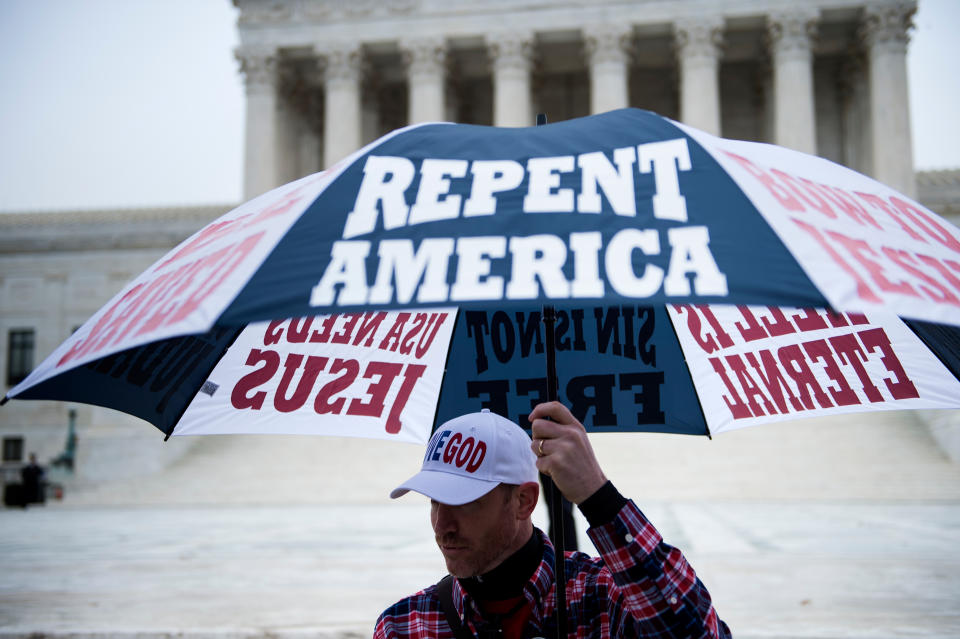 A protester outside the Supreme Court holds an umbrella that reads: Repent America.