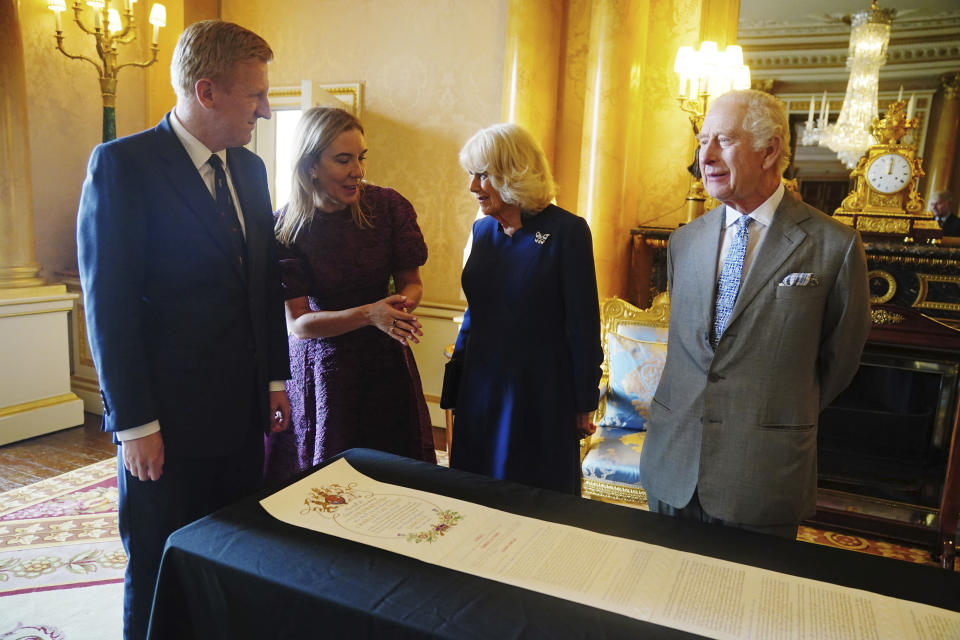 Britain's King Charles III and Queen Camilla are presented with the Coronation Roll, an official record of their Coronation, by the Clerk of the Crown in Chancery, Antonia Romeo, and the Deputy Prime Minster, Oliver Dowden, at Buckingham Palace, central London, Wednesday May 1, 2024. King Charles III gaped at the 70-foot-long (21.4-meter) hand-lettered scroll as it was presented to him earlier this week at Buckingham Palace, thanking the artisans who produced the document that serves as the official record of his coronation almost a year ago. (Victoria Jones/PA via AP)