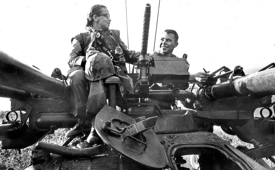 Photojournalist Dickey Chapelle and Pfc. David Cooper, of Gary, Ind., ride atop a tank in 1965.