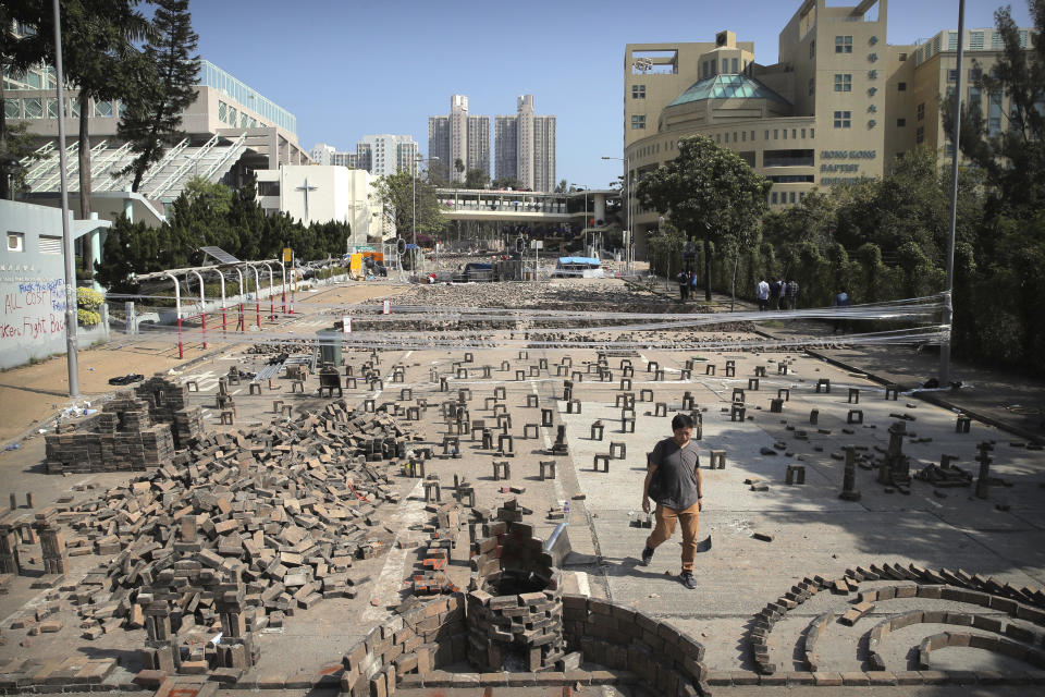 A man walks past barricades built by protesters at Hong Kong Baptist University in Hong Kong, Friday, Nov. 15, 2019. Protesters who have barricaded themselves in a Hong Kong university partially cleared a road they were blocking and demanded that the government commit to holding local elections on Nov. 24. (AP Photo/Kin Cheung)