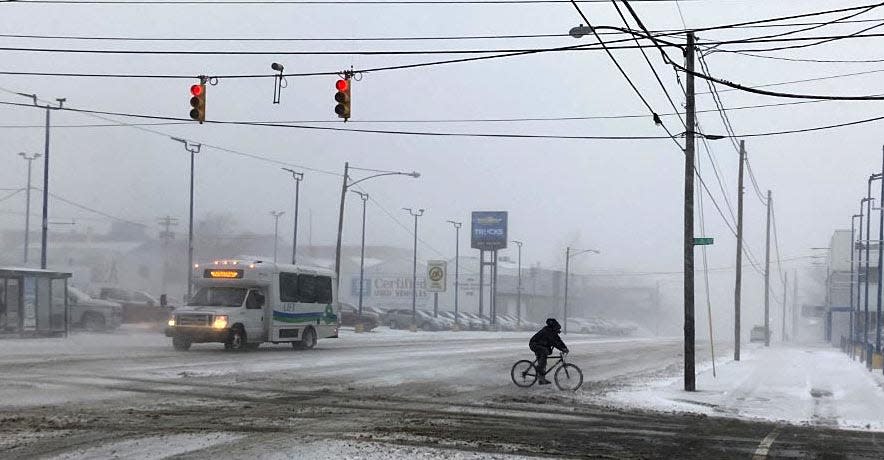 A bicyclist pedals across a snow-covered State Street near 21st Street around 8:15 a.m. Friday. A massive winter storm with snow, falling temperatures and high winds is expected to remain in the area through Christmas Day. Photo taken Dec. 23, 2022.