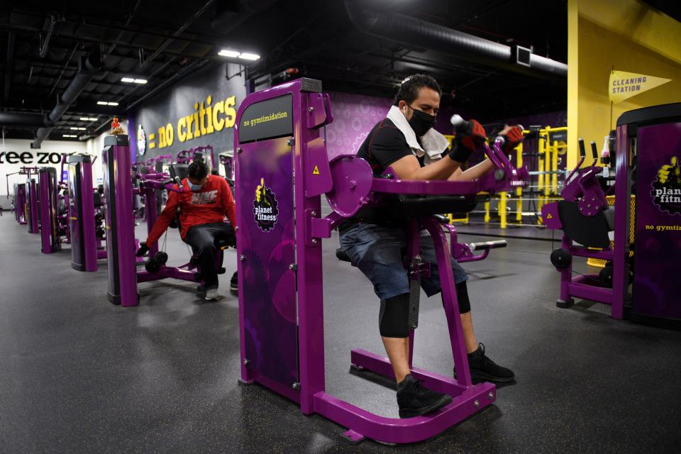 A customer wears a face mask as they lift weights while working out inside a Planet Fitness Inc. gym as the location reopens after being closed due to the Covid-19 pandemic, on March 16, 2021 in Inglewood, California. - Los Angeles County is allowing fitness centers and gyms to reopen for indoor workouts at ten percent capacity with customers wearing face masks under Covid-19 public health guidelines. (Photo by Patrick T. FALLON / AFP) (Photo by PATRICK T. FALLON/AFP via Getty Images)