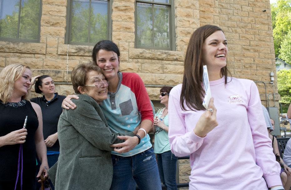 Jennifer Rambo, right, smiles as her partner Kristin Seaton, center, hugs Sheryl Maples, left, the lead attorney who filed the Wright v. the State of Arkansas lawsuit, Saturday, May 10, 2014, in Eureka Springs, Ark. A judge overturned amendment 83 Friday, which banned same-sex marriage in the state of Arkansas. (AP Photo/Sarah Bentham)