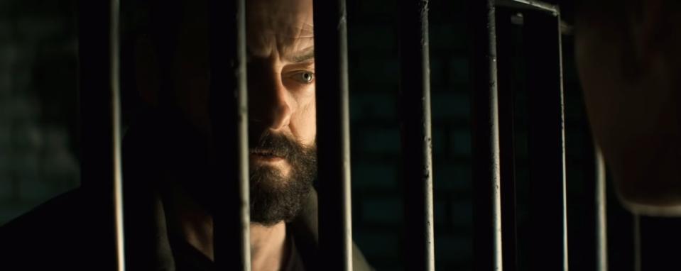 An intense, bearded stranger stares at someone through the eye of a jail cell in "Let Us Prey"
