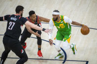 Utah Jazz guard Mike Conley (10) drives the ball on Portland Trail Blazers center Jusuf Nurkic (27) as guard CJ McCollum, rear, also defends during the first half of an NBA basketball game Thursday, April 8, 2021, in Salt Lake City. (AP Photo/Isaac Hale)