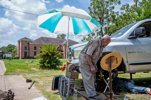 PHOTO: A mechanic works on a neighbors vehicle during a heatwave on July 21, 2022 in Houston. (Brandon Bell/Getty Images)