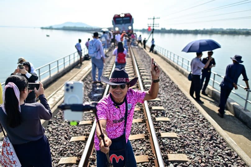 Un turista que viaja a bordo del popular "tren flotante" toma fotografías a lo largo de las vías del tren durante una parada en el centro de la presa de Pasak Jolasid.