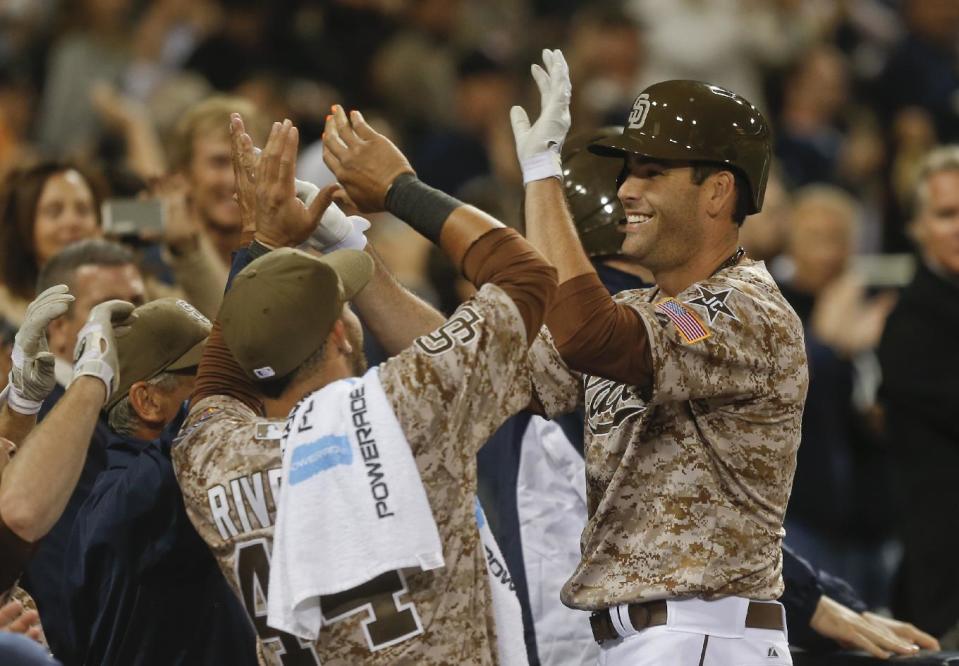 San Diego Padres Seth Smith is greeted at the dugout after his game tieing home run against the Los Angeles Dodgers in the eighth inning of the opening game of Major League baseball in the United States Sunday, March 30, 2014, in San Diego. (AP Photo/Lenny Ignelzi)