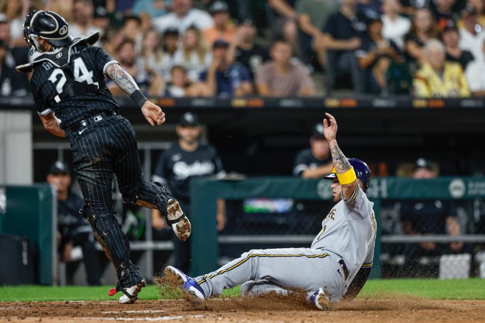 Brewers catcher Victor Caratini slides across the plate safely as the throw home goes over the head of White Sox catcher Yasmani Grandal during the sixth inning Friday night at Guaranteed Rate Field.