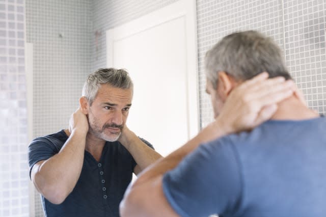 Mature man looking in bathroom mirror