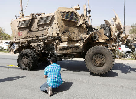 An Afghan photographer takes picture of a damaged Danish convoy at the site of a car bomb attack in Kabul, Afghanistan September 24, 2017. REUTERS/Omar Sobhani