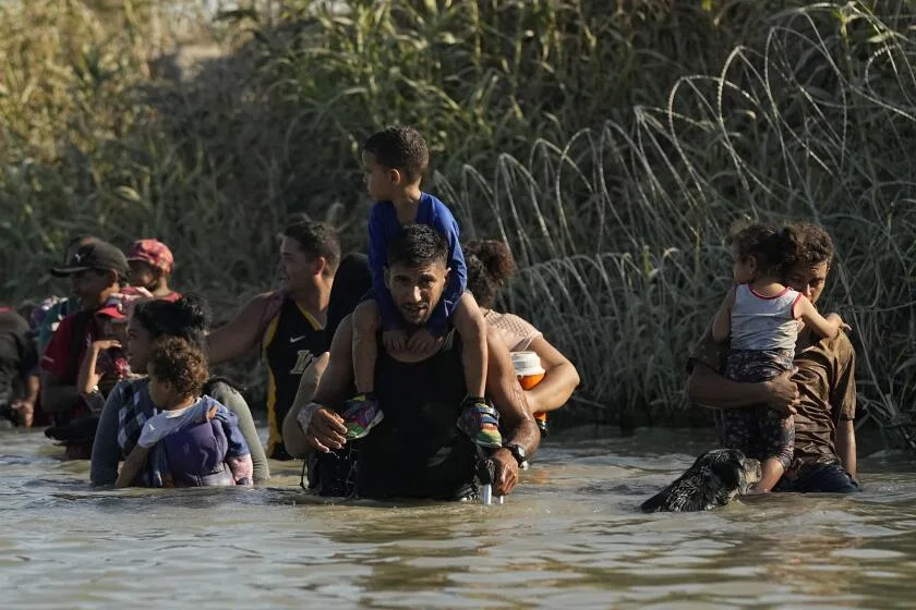 Migrants navigate around concertina wire along the banks of the Rio Grande after crossing from Mexico into the U.S., Tuesday, Aug. 1, 2023, in Eagle Pass, Texas. Concertina wire and newly place buoys being used as a floating barrier, are making in more difficult and dangerous to cross the Rio Grande. (AP Photo/Eric Gay)