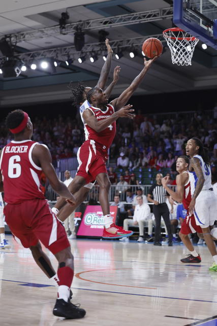 In a photo provided by Bahamas Visual Services, Arkansas' Davonte Davis goes for a layup with Memphis' Jaykwon Walton close behind during an NCAA college basketball game in the Battle 4 Atlantis at Paradise Island, Bahamas, Thursday, Nov. 23, 2023. (Tim Aylen/Bahamas Visual Services via AP)