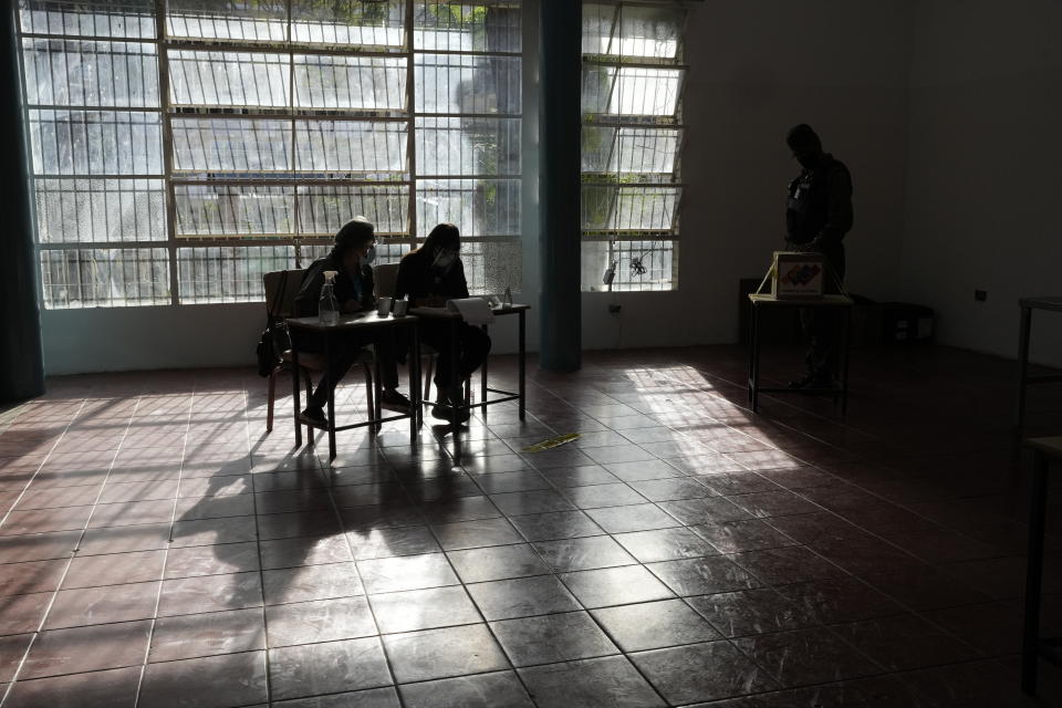 Electoral officials watch as a soldier votes during regional elections at a polling station at the Fermin Toro school in Caracas, Venezuela, Sunday, Nov. 21, 2021. Venezuelans go to the polls to elect state governors and other local officials. (AP Photo/Ariana Cubillos)