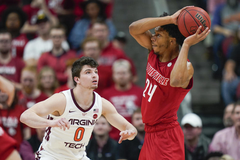 Louisville forward Dwayne Sutton (24) passes the ball around Virginia Tech guard Hunter Cattoor (0) during the first half of an NCAA college basketball game, Sunday, March 1, 2020, in Louisville, Ky. (AP Photo/Bryan Woolston)