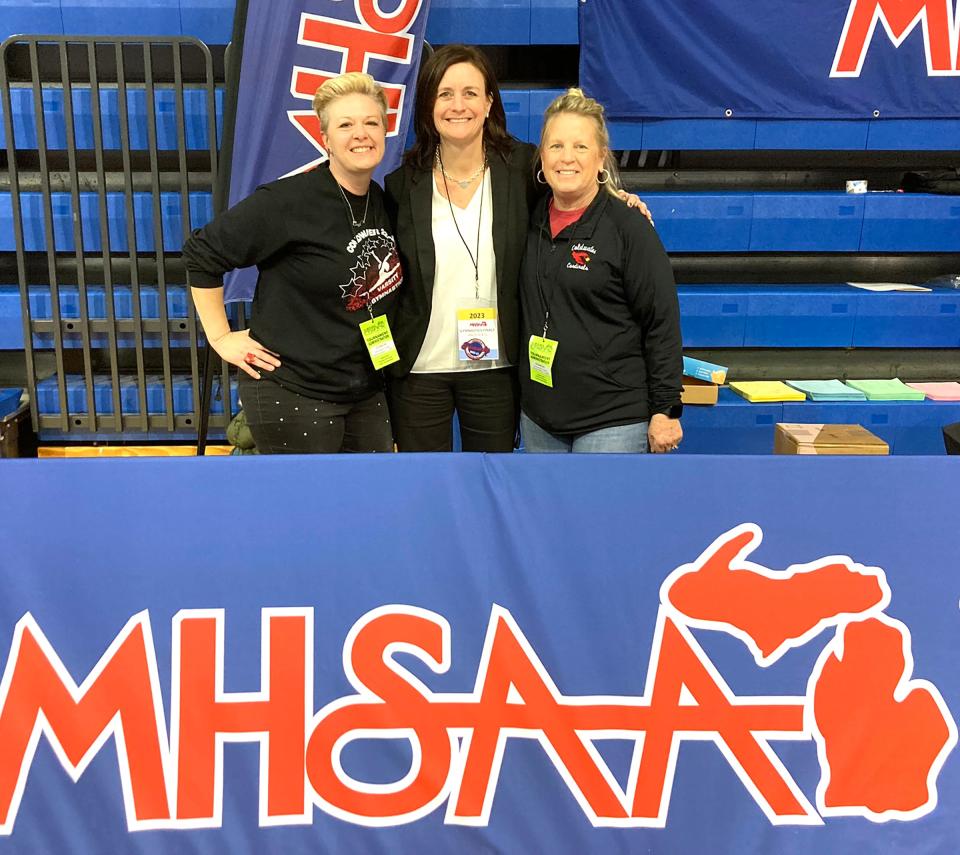 Coldwater coaches Kim Nichols (left) and Janet Kahler (right) pose with Coldwater alumni Courtney Dean who was honored at the state finals for 20 years of service as an MHSAA official