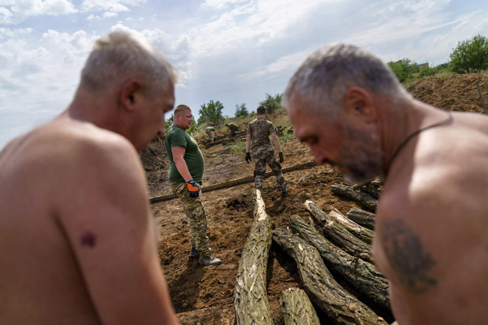 Soldiers with the Dnipro-1 regiment place logs to fortify their position near Sloviansk, Donetsk region, eastern Ukraine, Friday, Aug. 5, 2022. From a position on the outskirts of the city, members with the Ukrainian military unit are expanding a network of trenches and digging bunkers capable of protecting soldiers against mortar strikes and phosphorous bombs. (AP Photo/David Goldman)