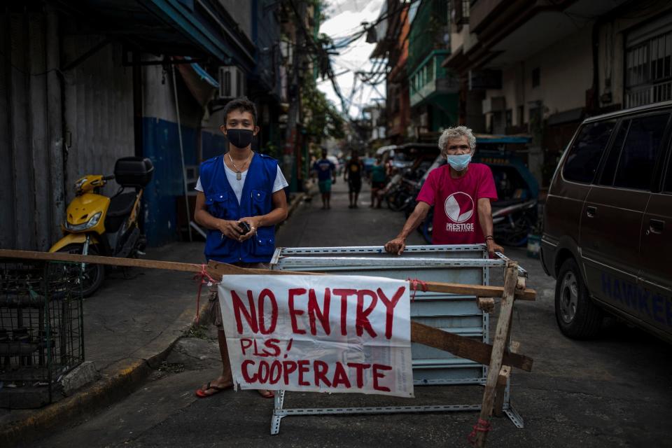 Angel Navarro and Nonoy Zapanta pose for a portrait as they guard a makeshift barricade blocking one of the entrances to Barangay 46 to prevent the spread of COVID-19 in their village on March 20, 2020 in Manila, Philippines.