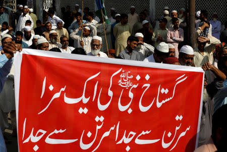 Supporters of religious and political party Jamaat-e-Islami (JI) listen to the speech of their leader during a protest, after the Supreme Court overturned the conviction of a Christian woman sentenced to death for blasphemy against Islam, in Karachi, Pakistan November 2, 2018. The banner reads: "Decapitation is retribution of Prophet's blasphemer". REUTERS/Akhtar Soomro/File Photo