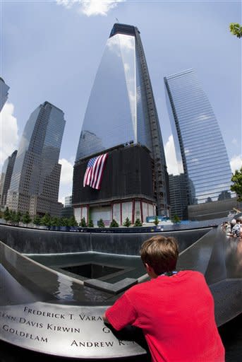 A visitor to the National September 11 Memorial get a view of one of the memorial pools and One World Trade Center, center, Thursday, June 14, 2012 in New York. President Barack Obama is scheduled to visit the site later Thursday. (AP Photo/Mark Lennihan)