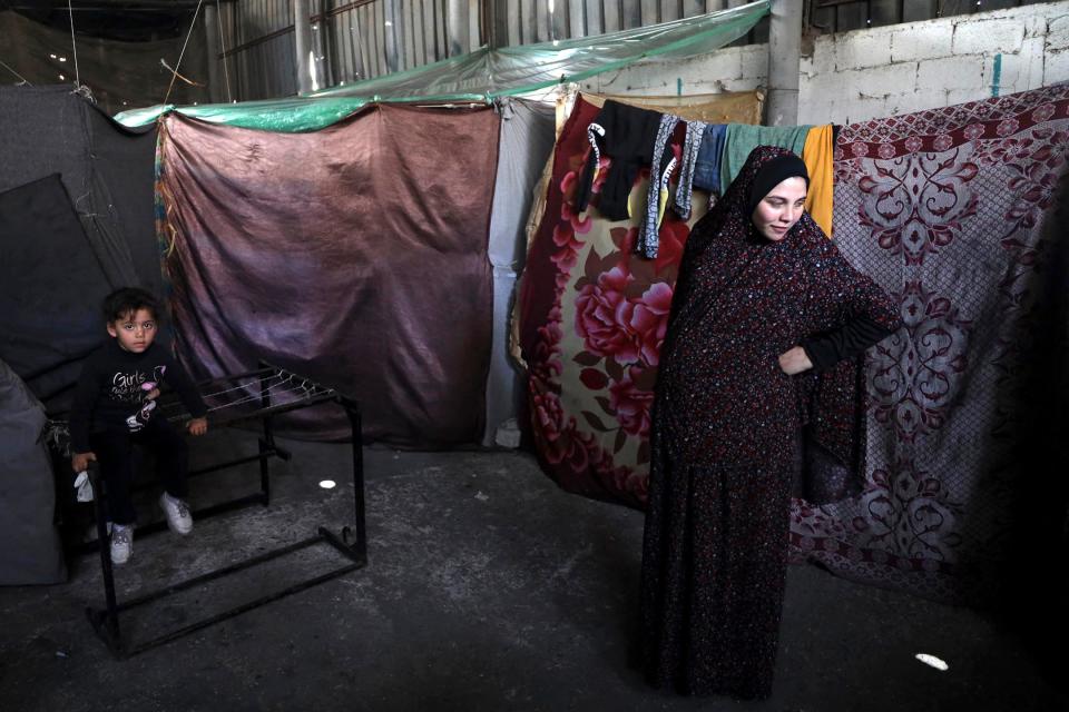 A pregnant Palestinian woman displaced from northern Gaza stands in a warehouse where she is taking shelter in February.