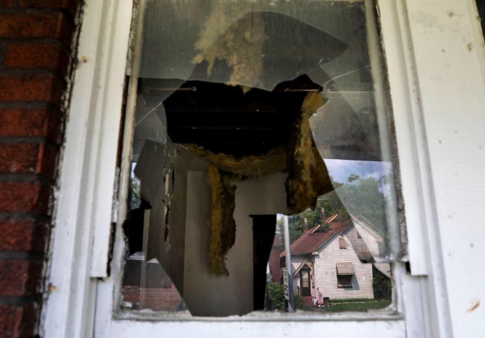 A lived in property is seen reflected in the broken window of an abandoned property along Genevieve Avenue in the Walnut Park East neighborhood of St. Louis on Thursday, July 22, 2021. The abandoned property is one in a chain of five abandoned and dilapidated houses on the street.