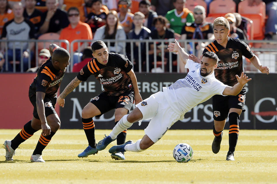 Los Angeles Galaxy midfielder Sebastian Lletget, center, falls while trying to move the ball between Houston Dynamo midfielder Boniek García, left, midfielder Matías Vera (22) and midfielder Memo Rodriguez (8) during the first half of an MLS soccer match Saturday, Feb. 29, 2020, in Houston. (AP Photo/Michael Wyke)