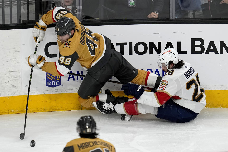 Vegas Golden Knights center Ivan Barbashev (49) and Florida Panthers defenseman Josh Mahura (28) battle for the puck during the second period of Game 1 of the NHL hockey Stanley Cup Finals, Saturday, June 3, 2023, in Las Vegas. (AP Photo/Abbie Parr)