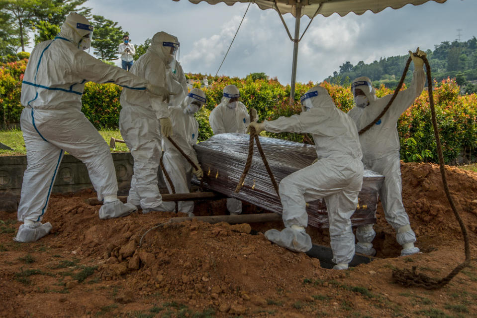 Health workers in PPE suits bury the body of a Covid-19 victim at a Christian cemetery in Semenyih, Selangor. — Picture by Shafwan Zaidon